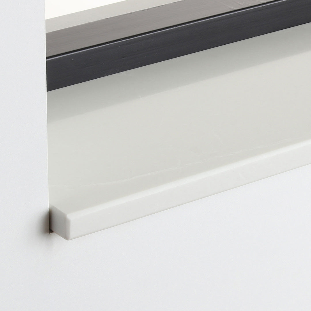 Detail van de witte gepolijste composiet vensterbank Bottechino Grey onder het raam.