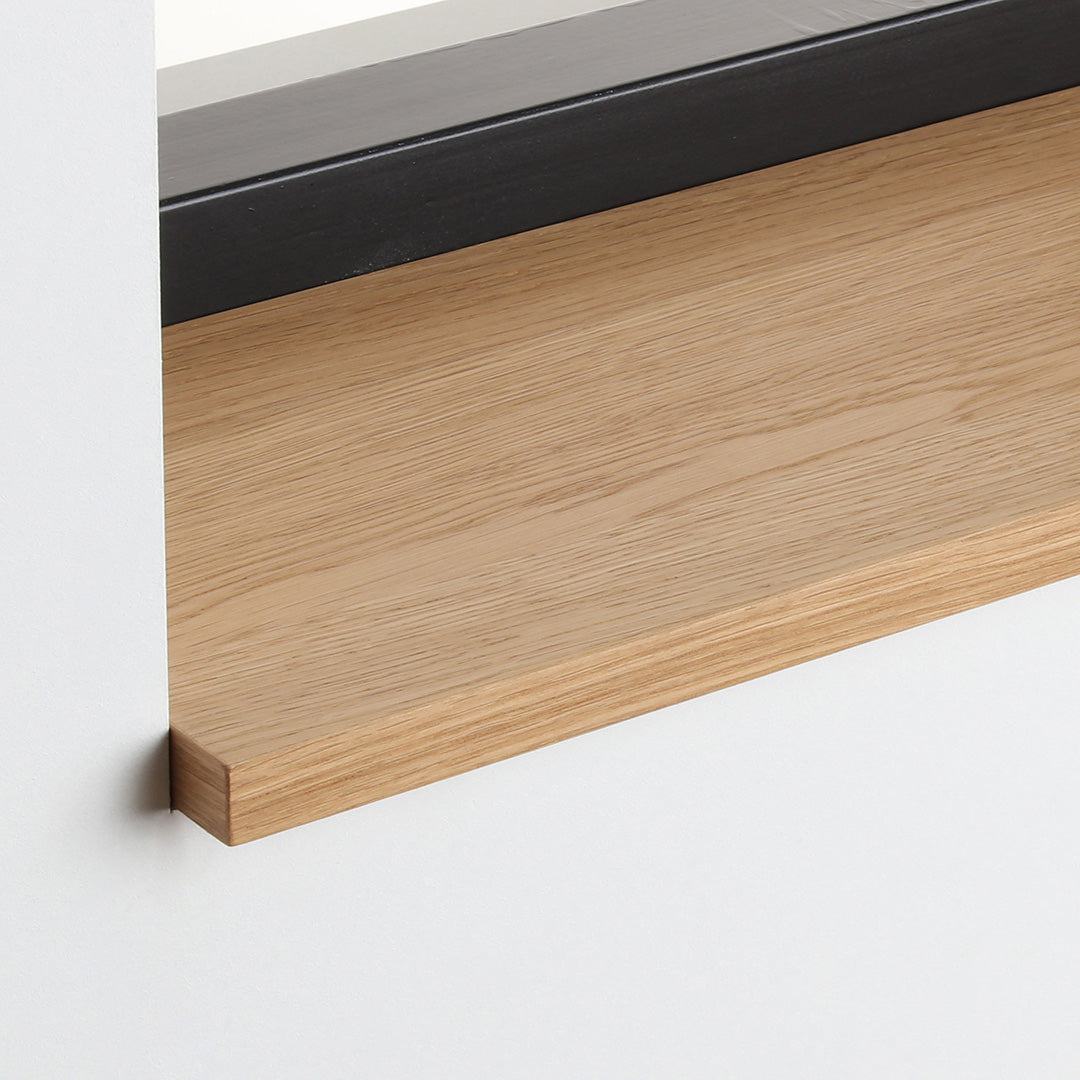 Detail van de eiken gefineerde vensterbank met matte blanke lak onder het raam.