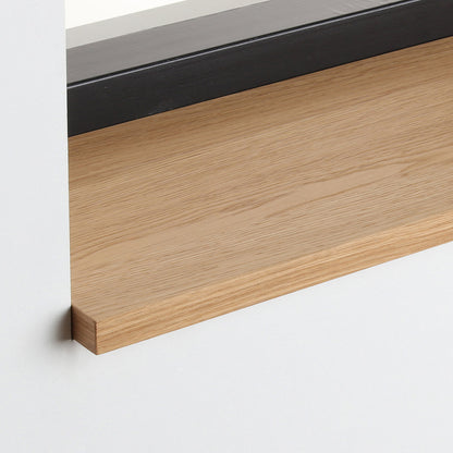 Detail van de eiken gefineerde vensterbank met matte blanke lak onder het raam.