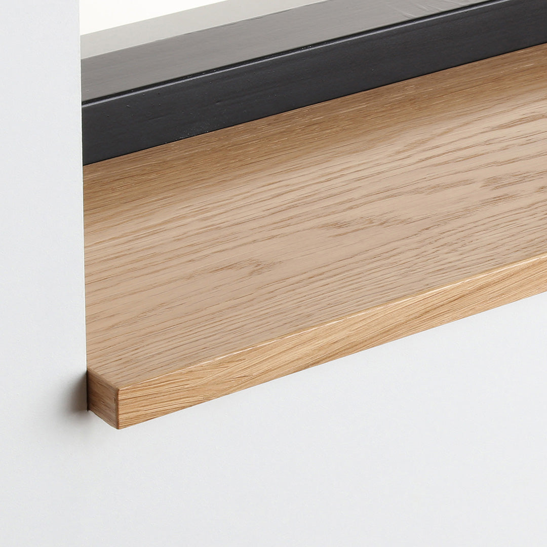 Detail van de eiken gefineerde vensterbank met zijdeglans blanke lak onder het raam.