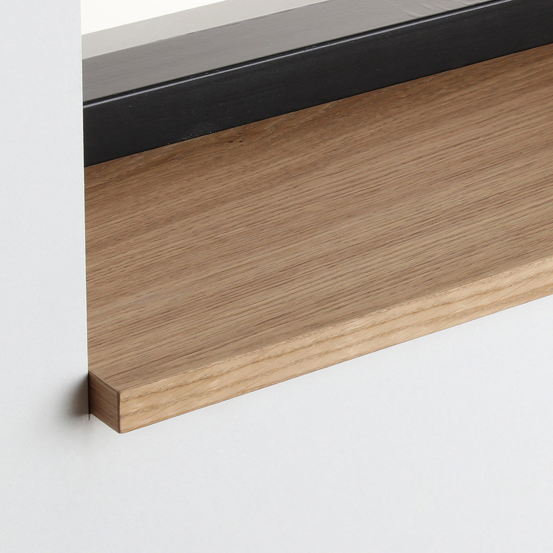 Detail van de eiken gefineerde vensterbank Sandstone met matte beits onder het raam.