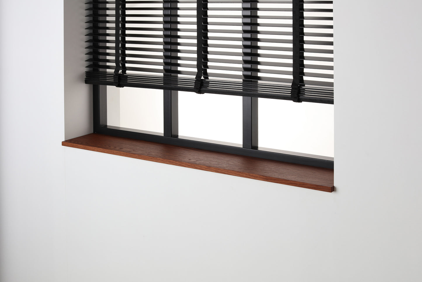 Eiken gefineerde vensterbank Smoked Oak met matte beits onder een zwart raam met jaloezieën.
