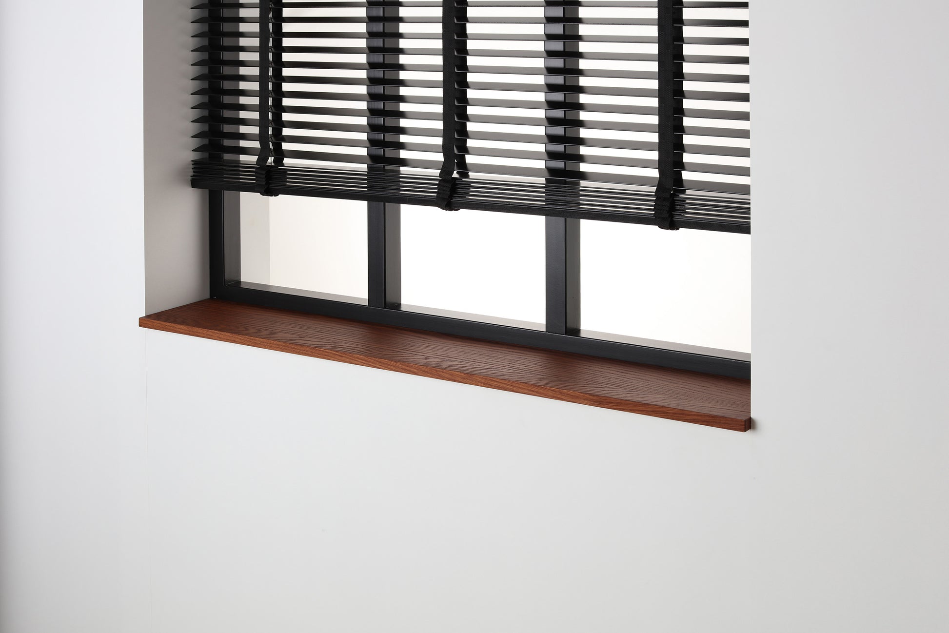 Eiken gefineerde vensterbank Smoked Oak met matte beits onder een zwart raam met jaloezieën.