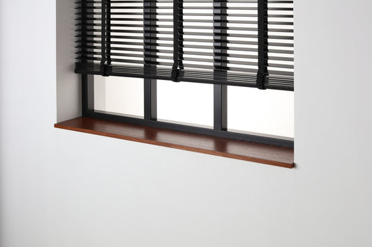 Eiken gefineerde vensterbank Smoked Oak met zijdeglans beits onder een zwart raam met jaloezieën.
