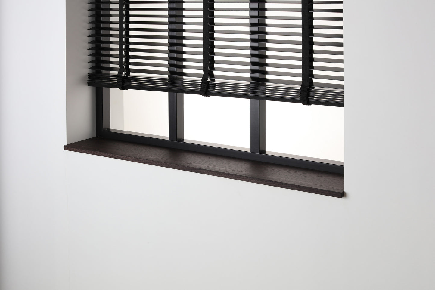 Eiken gefineerde vensterbank Wenge Masai met matte beits onder een zwart raam met jaloezieën.