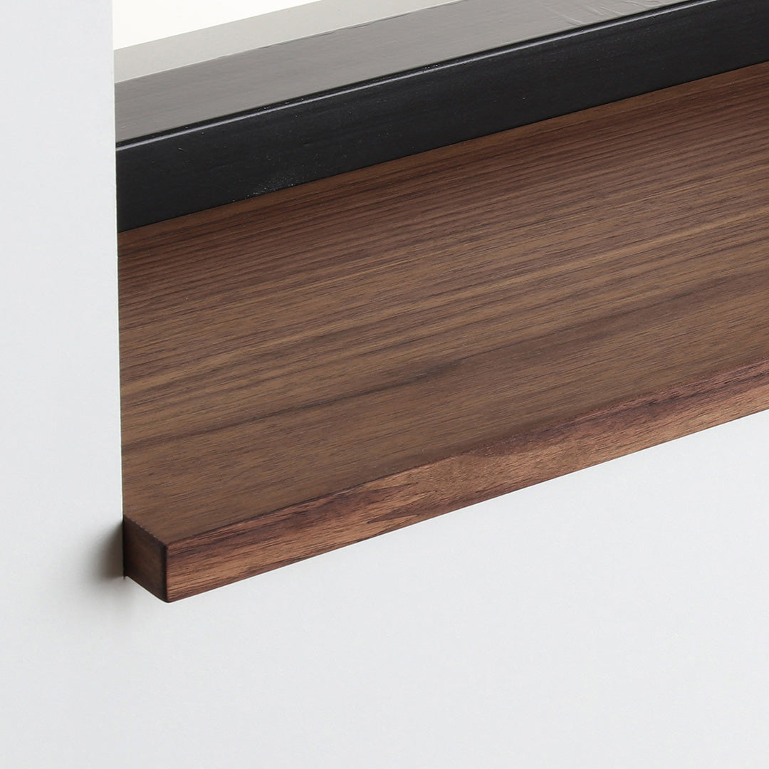 Detail van de noten gefineerde vensterbank met walnootkleurige afwerking onder het raam.
